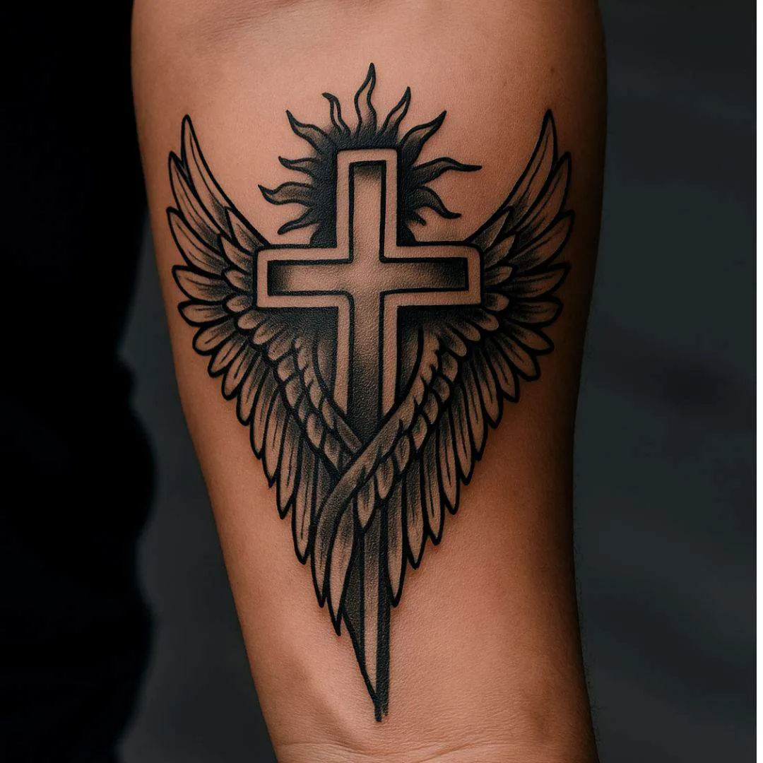 Blackwork cross-and-wings tattoo reference on a forearm, from Tat Ink
